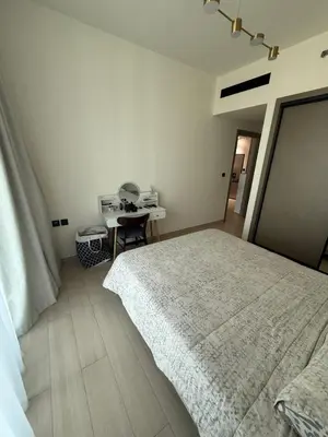 a white bedroom with a bed and a table at Modern 1BR in JVC, Pool & Gym Near Circle Mall in Dubai