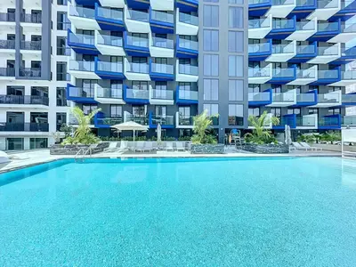 a swimming pool in front of a large apartment building at Modern 1BR in JVC, Pool & Gym Near Circle Mall in Dubai