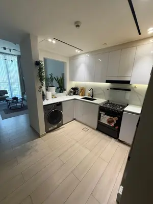 a kitchen with white cabinets and a stove top oven at Modern 1BR in JVC, Pool & Gym Near Circle Mall in Dubai