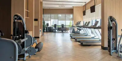 a gym with a row of treadmills and machines at Modern 1BR in JVC, Pool & Gym Near Circle Mall in Dubai