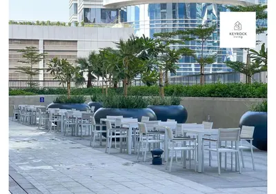 a row of white tables and chairs in front of a building at KeyRock Living - Modern 1BR at Zada Tower with Pool and Gym Facilities in Dubai
