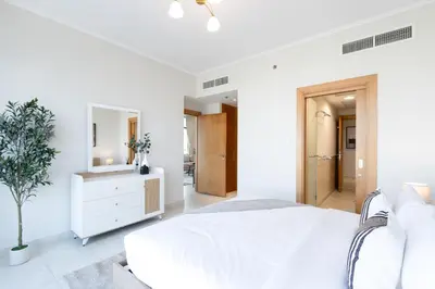 a white bedroom with a white bed and a mirror at Stylish 1BR Retreat with Pool and Stunning City View in Dubai