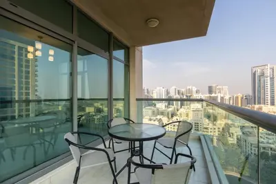 a table and chairs on a balcony with a view of the city at Stylish 1BR Retreat with Pool and Stunning City View in Dubai