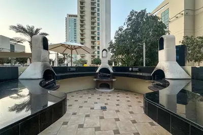 a pool with a bench and an umbrella in a city at Stylish 1BR Retreat with Pool and Stunning City View in Dubai