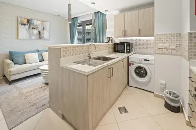 a kitchen with a sink and a washing machine at Seven Palm Elite 1BR-Infinity Pool & Skyline Views in Dubai