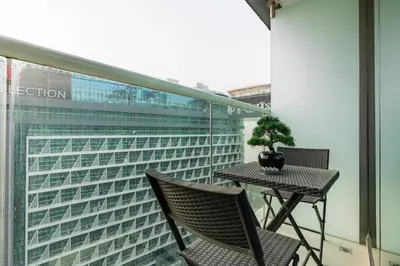 a table and chairs on a balcony with a building at Stylish 1-BR Beachfront Apt on SEVEN PALM Dubai in Dubai