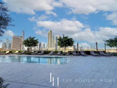 a swimming pool with chairs and a city skyline at LUX The Vida Burj Khalifa View Suite in Dubai