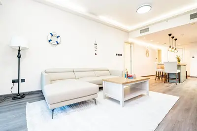 a living room with a white couch and a table at Escape24 Luxury 2BR with Large Balcony and Lake Views in Dubai