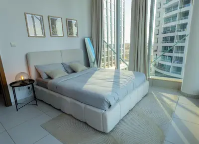 a white bed in a room with a large window at 1BHK at Panoramic Tower, Marina with Sea and Canal View in Dubai
