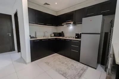 a kitchen with black cabinets and a white refrigerator at 1BHK at Panoramic Tower, Marina with Sea and Canal View in Dubai