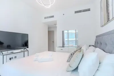 a white bedroom with a bed with pillows and a tv at TRPS - Beach Isle Tower 1, Dubai Harbour - Seaside Residence, Private Beach, Palm View in Dubai