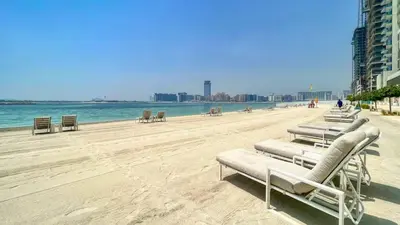 a beach with chaise lounges and chairs and the ocean at TRPS - Beach Isle Tower 1, Dubai Harbour - Seaside Residence, Private Beach, Palm View in Dubai