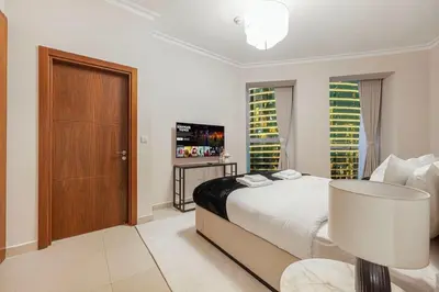 a white bedroom with a bed and a sliding door at Modern 4BR Suite Overlooking Downtown in Dubai
