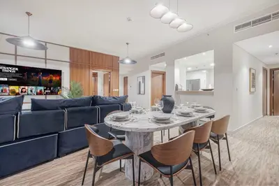 a living room with a table and a blue couch at Modern 4BR Suite Overlooking Downtown in Dubai