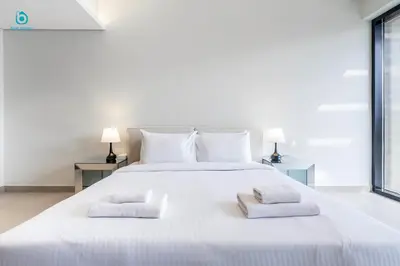 a white bed with two white towels on it at Blue Breeze Cozy 1 BR in JVC Al Serh Residence 11 in Dubai