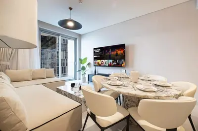 a living room with a table and white chairs at 2BR Luxury Hotel Amenities Dubai Mall Access in Dubai