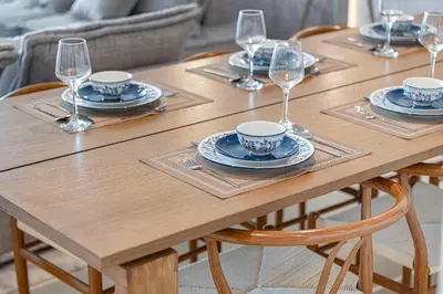 a wooden table with plates and wine glasses on it at 4Bedroom Luxury Stay in Downtown Views Dubai Mall in Dubai