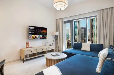 a living room with a blue couch and a large window at Cozy 1Bedroom Apartment Downtown Dubai Retreat in Dubai