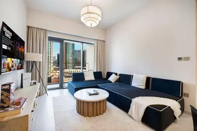 a living room with a blue couch and a table at Cozy 1Bedroom Apartment Downtown Dubai Retreat in Dubai
