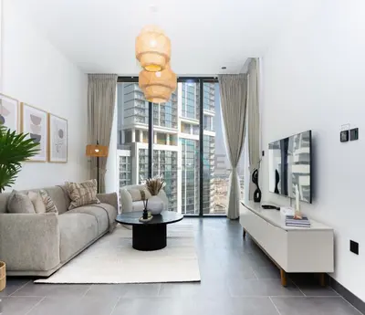 a living room with a couch and a table at Located Few Minutes Drive to Downtown Dubai, Burj Khalifa and Dubai Mall, Surrounded by Lush Green Community - Sobha Hartland The Crest Tower C by Deluxe Holiday Homes in Dubai