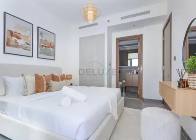 a white bedroom with a large bed and a table at Located Few Minutes Drive to Downtown Dubai, Burj Khalifa and Dubai Mall, Surrounded by Lush Green Community - Sobha Hartland The Crest Tower C by Deluxe Holiday Homes in Dubai