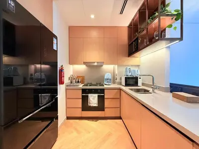 a kitchen with wooden cabinets and a black refrigerator at Center to Burj Khalifa I Brand New I High End in Dubai