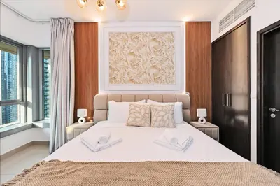 a bedroom with a large white bed with two tables at 22nd Floor Burj Khalifa View 5 Min Walk Dubai Mall in Dubai
