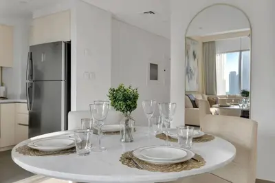 a white table with plates and glasses on it in a kitchen at Stylish 2 bedroom with Burj Khalifa View, connected to Dubai Mall in Dubai