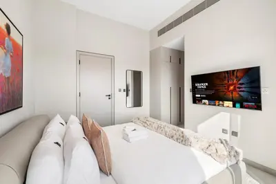 a white living room with a couch and a tv at 2.5BR Villa | PS5 & Private Pool | Near Dubai Mall in Dubai