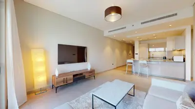 a living room with a tv and a couch and a table at Vacationer l Contemporary 1 Bedroom l Free Pool, Gym Access in Dubai
