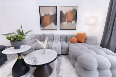 a living room with a blue couch and two tables at Central Location with Easy Access to Al Khail Road, Near Bus Stops, Supermarkets, Dining Spots, Minutes from Dubai Marina and Downtown - Belgravia Square B, JVC by Deluxe Holiday Homes in Dubai