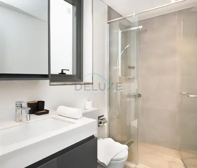 a bathroom with a toilet and a glass shower at Central Location with Easy Access to Al Khail Road, Near Bus Stops, Supermarkets, Dining Spots, Minutes from Dubai Marina and Downtown - Belgravia Square B, JVC by Deluxe Holiday Homes in Dubai