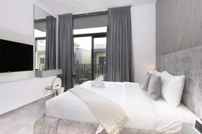 a bedroom with a white bed and a large window at Central Location with Easy Access to Al Khail Road, Near Bus Stops, Supermarkets, Dining Spots, Minutes from Dubai Marina and Downtown - Belgravia Square B, JVC by Deluxe Holiday Homes in Dubai