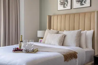 a bed with a bottle of champagne and wine glasses at Frank Porter - Peninsula One in Dubai