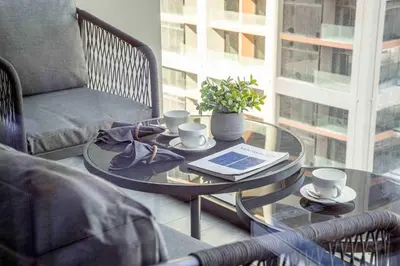 a glass coffee table with a book and cups on it at Frank Porter - Peninsula One in Dubai