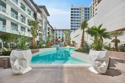a pool in the middle of a building with palm trees at Pool View Studio Near to circle mall - Icon casa Living in Dubai
