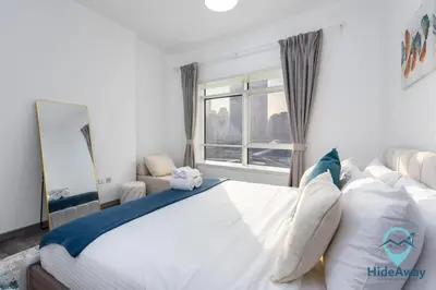 a bedroom with a large white bed with a window at Stunning 1BR l JLTl Steps to Metro! in Dubai