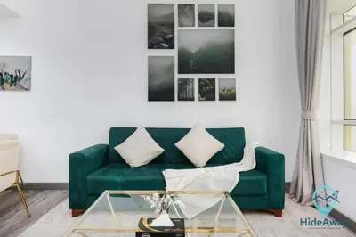 a living room with a green couch and a table at Stunning 1BR l JLTl Steps to Metro! in Dubai