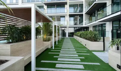 an office building with a walkway with green grass at Tranquil 1BR in Binghatti Amber with Free Pool & Gym! in Dubai