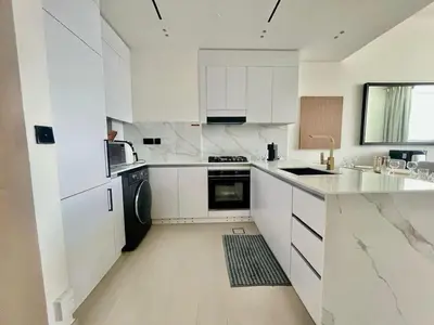 a white kitchen with white cabinets and a black appliance at Tranquil 1BR in Binghatti Amber with Free Pool & Gym! in Dubai