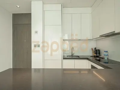 a kitchen with white cabinets and a stainless steel counter top at Zapbed House-luxury one bedroom apartment in Residence 16 in Dubai
