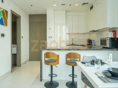 a kitchen with two bar stools and a counter at Zapbed House-luxury one bedroom apartment in Residence 16 in Dubai