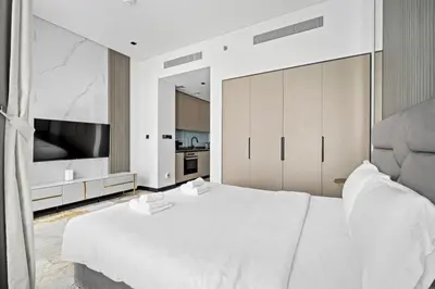 a white bedroom with a large bed and a television at Luxury Studio Business Bay Short Stays Long Stays in Dubai