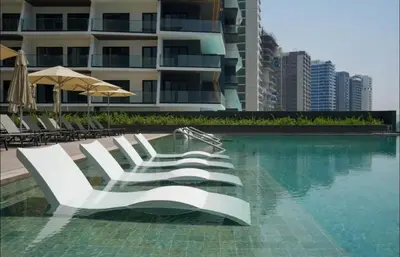 a swimming pool with white chairs and a building at Luxury Studio Business Bay Short Stays Long Stays in Dubai
