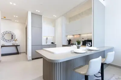 a kitchen with a large island with white chairs at Modern 1B with Private Jacuzzi Binghatti Phantom, JVC in Dubai