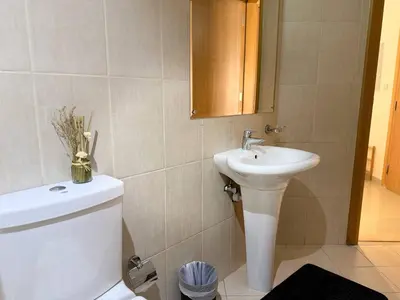 a bathroom with a sink and a toilet and a mirror at ASHRI HH | Spacious Studio in Arjan in Dubai