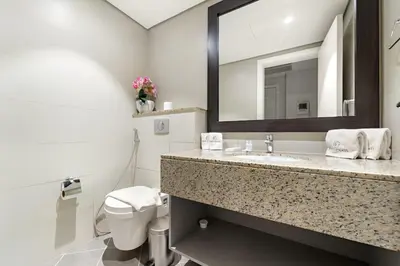 a bathroom with a sink and a toilet and a mirror at FIRST CLASS 1BR Serene Sea View Royal Amwaj in Dubai