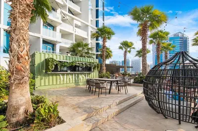 a patio with a table and chairs and palm trees at Sleek Home in Business Bay with Panoramic Views in Dubai