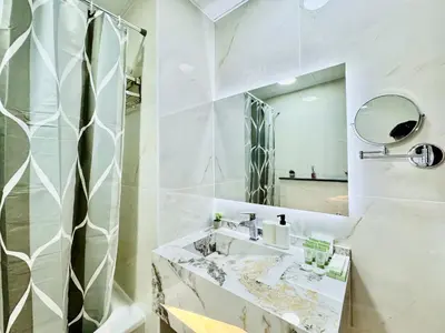 a white bathroom with a sink and a mirror at Cosmos Living Work-Friendly with Easy Metro Access in Dubai