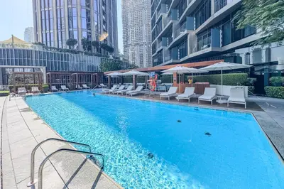 a swimming pool with chairs and umbrellas on a building at High-End 2Bedroom Near Dubai Opera & Mall in Dubai